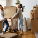 Young couple carrying big cardboard box at new home.Moving house.